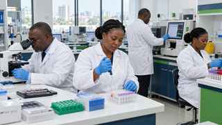 Four laboratory staff in white coats at work: one looks into a microscope, one pipettes samples into test tubes, one uses an analyser, and one prepares sample tubes